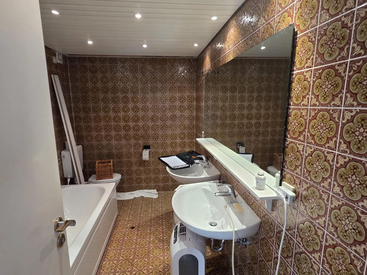 Badezimmer mit 70er-Jahre-Musterfliesen vor der Sanierung