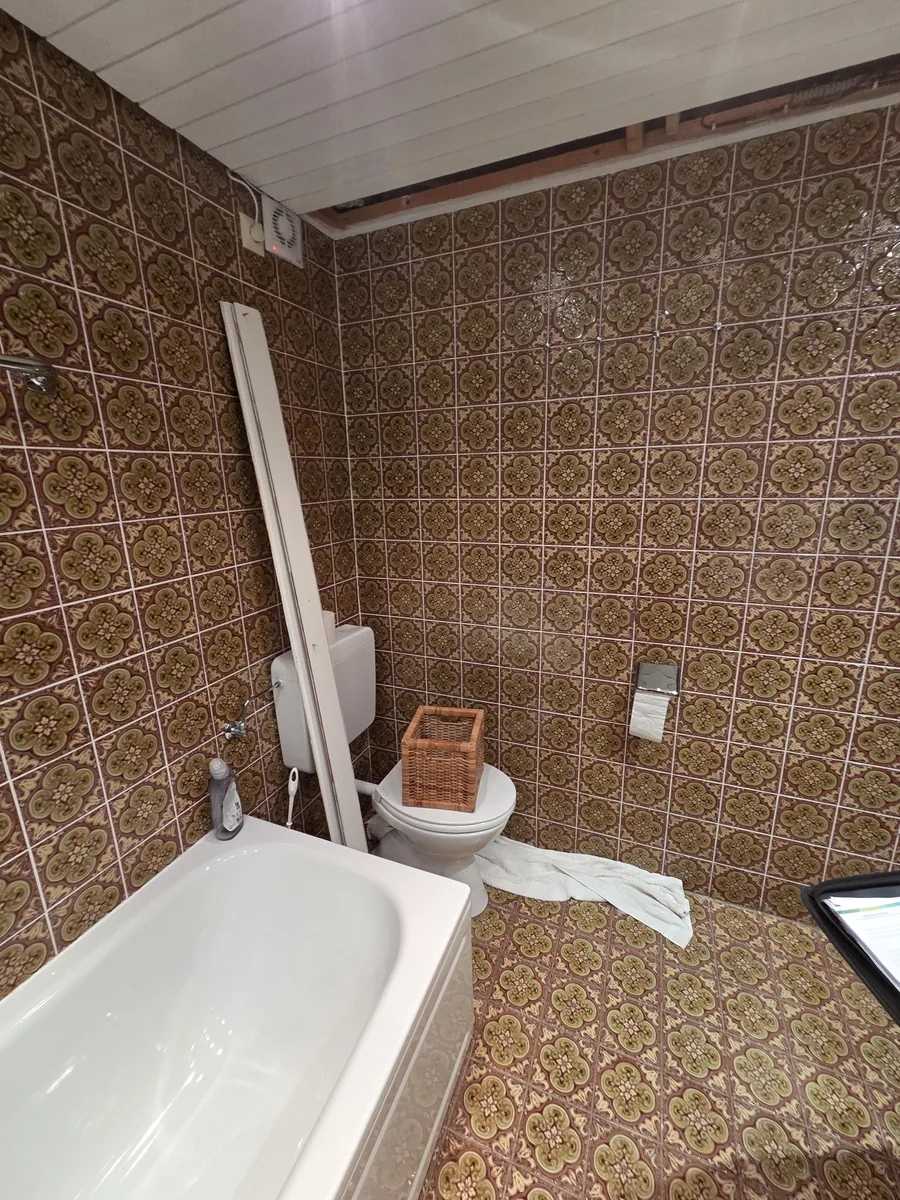 Altes Bad mit Musterfliesen und Stand-WC vor der Sanierung